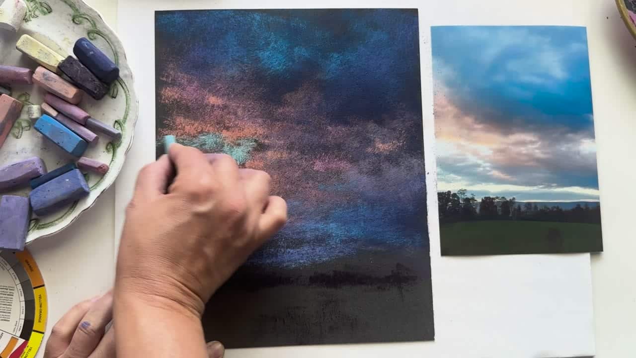 Hands painting a soft pastel sunset landscape