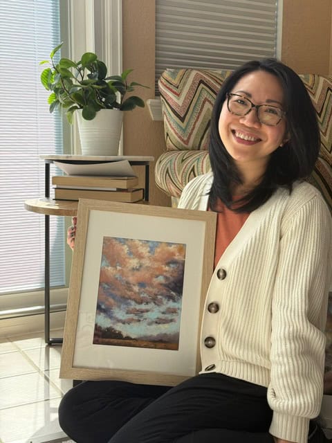 LH Vahn holding her framed soft pastel sky painting